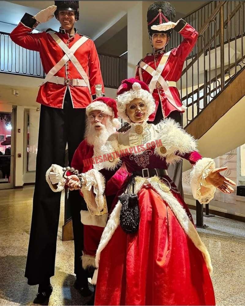 Corporate Santa for a Naples, FL office party: Santa, Mrs. Claus and two nutcracker soldiers on stilts indoors.