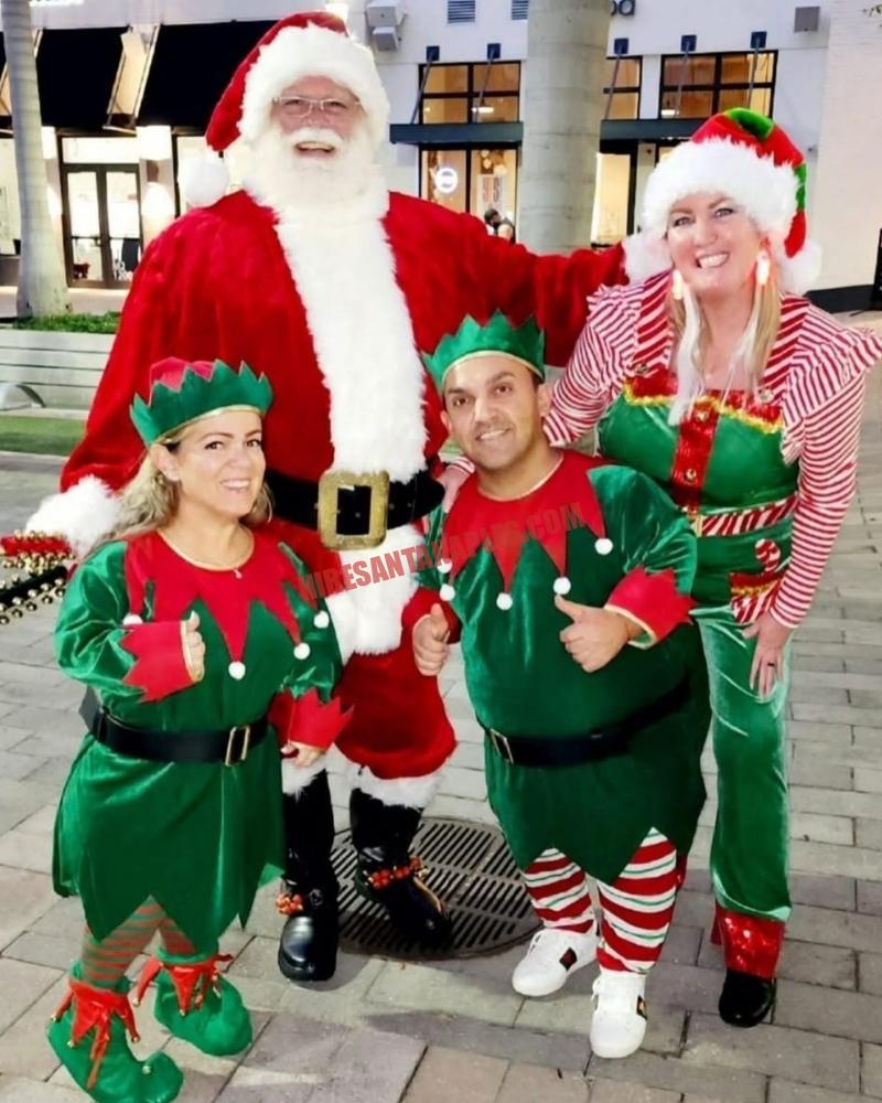 Santa for hire in Estero, FL: Santa with three elves on a plaza as evening comes on.