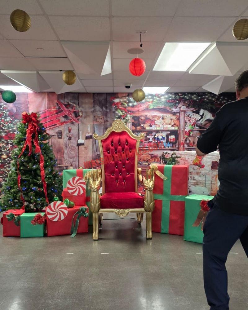 Santa photos in Naples, FL: gold chair among gift boxes, a lit tree, and a workshop backdrop.